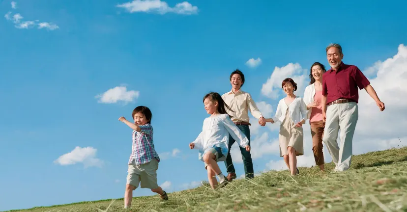一家三代在草坡上牵手奔跑