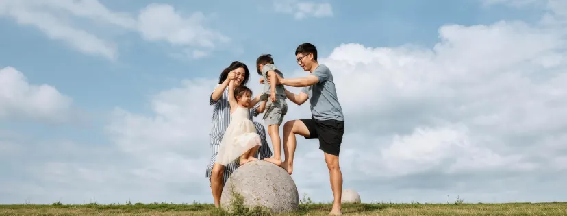 一家四口在草地上的大石球旁嬉戏