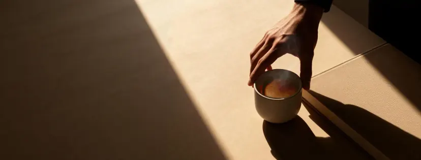 A hand holding a steaming cup of nutritious drink in the sunlight