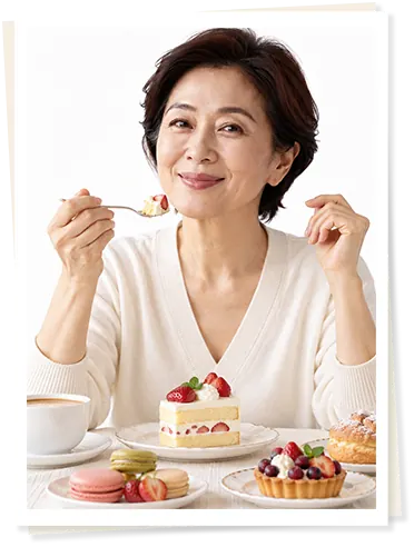 中年女士微笑着吃蛋糕,桌上摆满草莓蛋糕、马卡龙和甜点