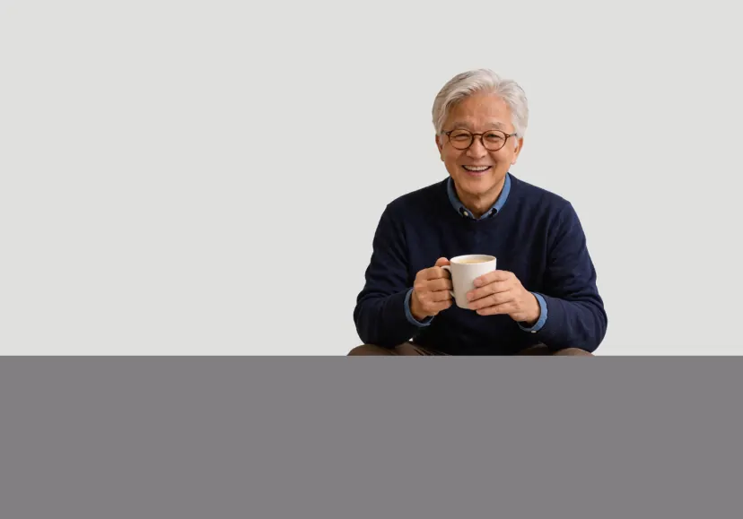 戴眼镜的银发长者双手捧着一杯热饮,开心地微笑