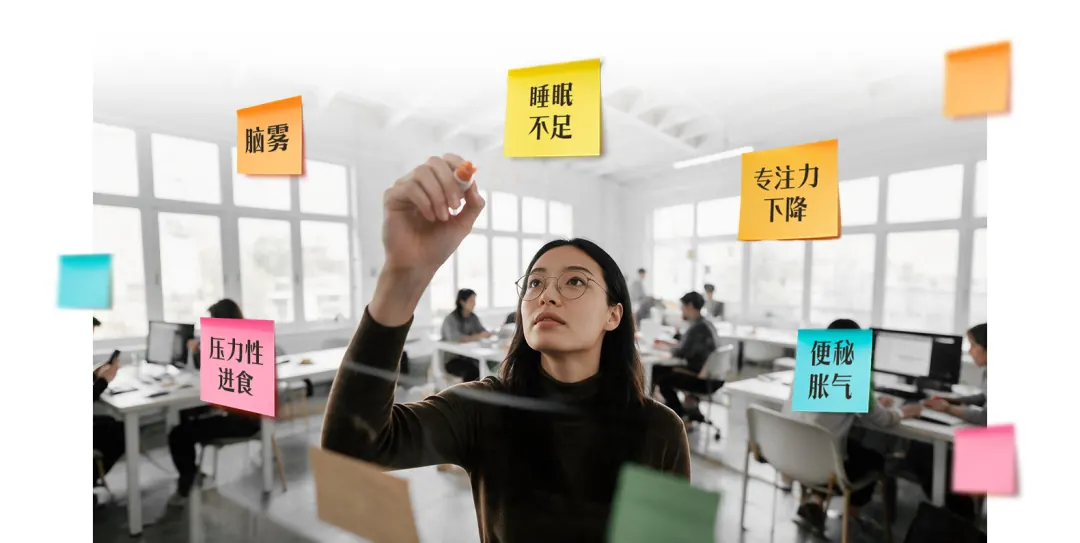 办公室里戴眼镜的女士伸手贴便利贴,便利贴上写着脑雾、睡眠不足、专注力下降、压力性进食、便秘胀气